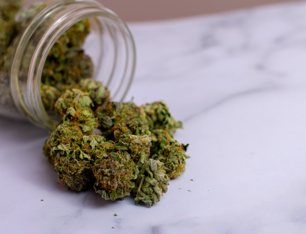 Image of cannabis in a jar pouring out onto a granite countertop