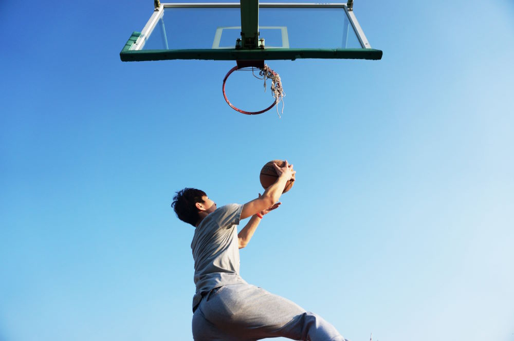 Image of a basketball player doing a layup into a hoop.
