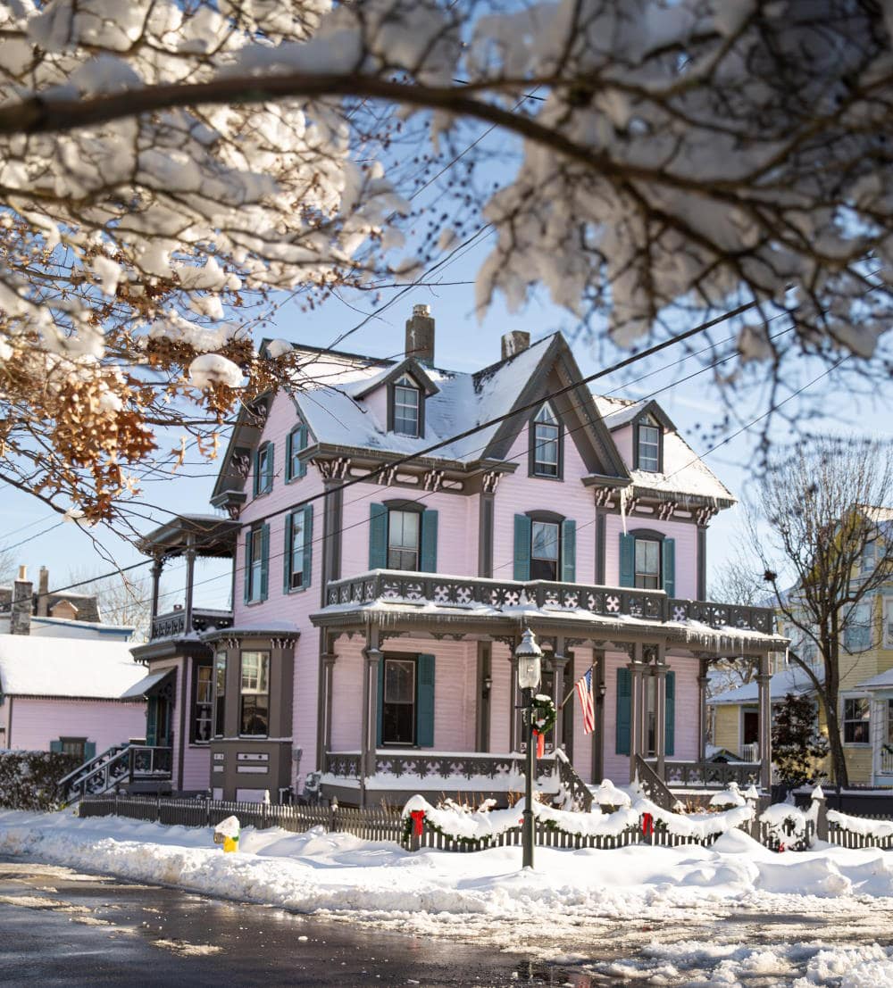Image of a charming Victorian house in Cape May NJ in the winter with snow on the front lawn