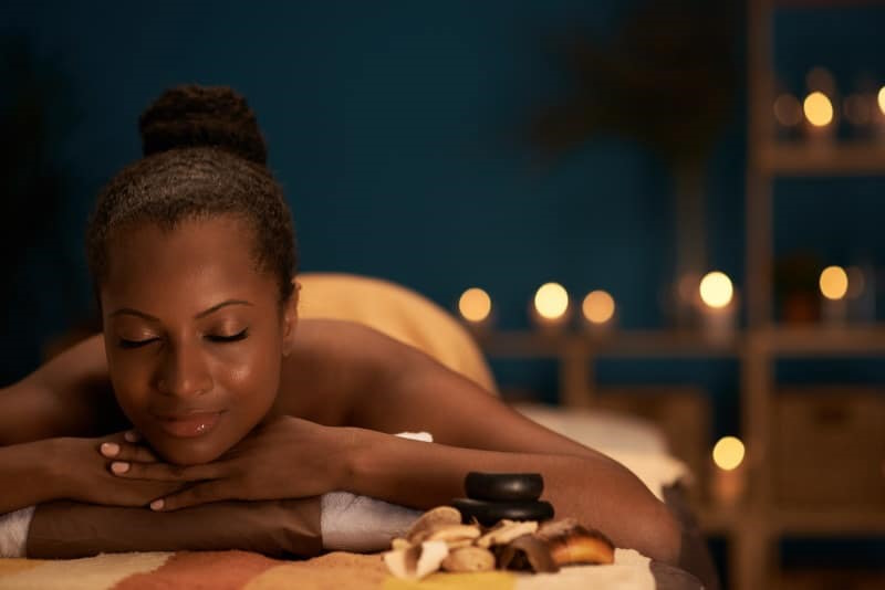 Image of an African American woman laying on a spa bed outside at night