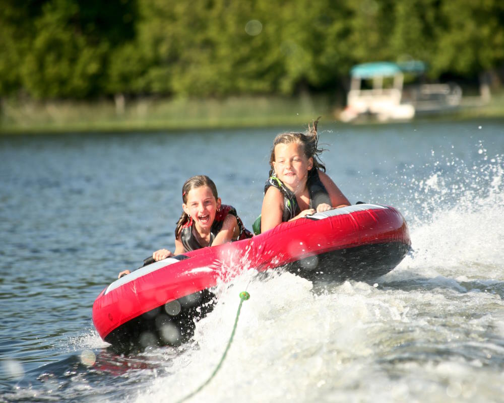 image of 2 girls being towed high speed on a round tube on Lake Hopatcong.