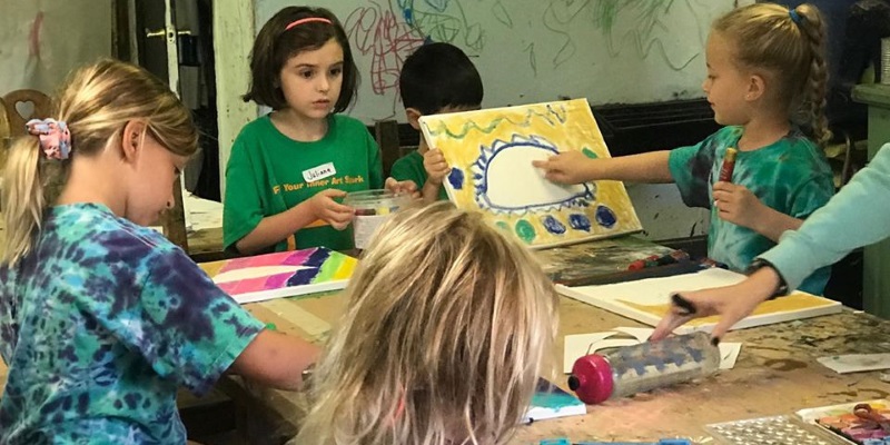 Photo a  children sitting around a table painting and drawing at a art day camp in NJ