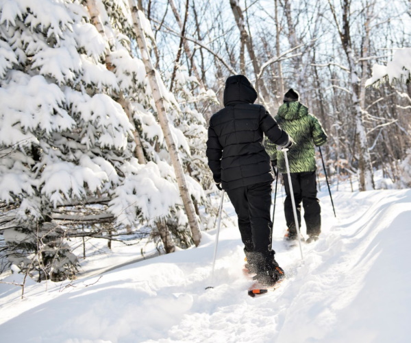 Image of two people snowshoeing through the mountains at Camelback Resort as an example of a fun day trip in the Poconos PA