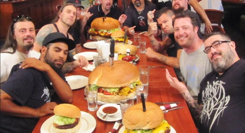 Photo of a bunch of guys at a table with huge burgers on the table as part of the Clinton Station Diner's unique challenge where you can win money if you eat their massive burgers.