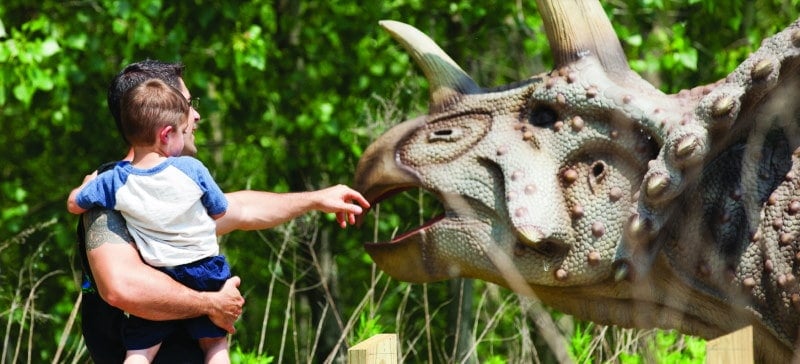 Photo of a father holding his young son in front of a dinosaur at Field Station amusement park in Leonia NJ