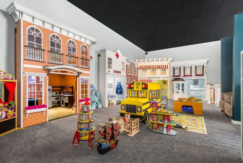 Photo of a very unique play place in North Jersey called Hudsons House of Play that depicts an indoor town with houses that kids can play in and a school bus in the middle of the street