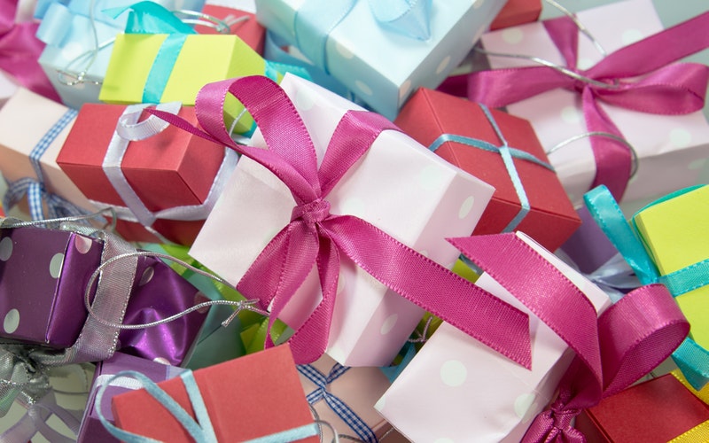 Photo 12 gifts piled up colorfully wrapped in different colored paper with bows on them