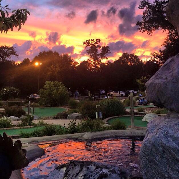 A sunset photo of a waterfall and 4 holes at the Paramus Mini Golf Course in located in North Jersey