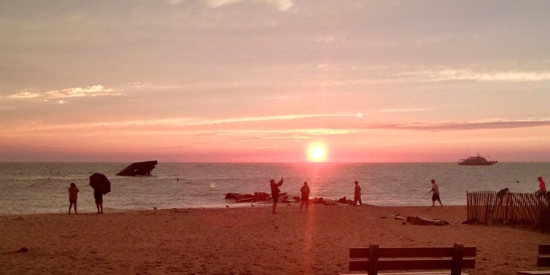 Photo of a sunset at Sunset Beach in Cape May New Jersey with people walking on the sand.