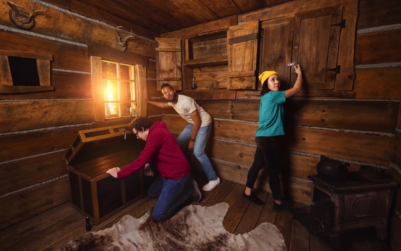 Photo of 3 people trying to find their way out of an escape room
