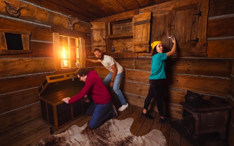 Photo of 3 people trying to find their way out of an escape room