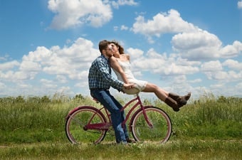 Image of Two People Kissing on a Bicycle in a Grassy Field as an example of a romantic New Jersey date idea