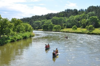 Image of people on kayaks on a river surrounded by trees showing an adventure getaway in NJ