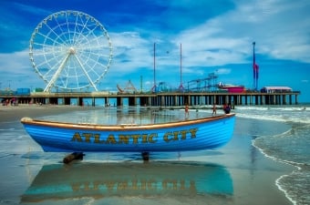 Image of the Ferris Wheel and Atlantic City Boardwalk with a small row boat on beach sand in the front