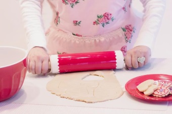Image of a girl using a rolling pin to roll out dough as part of a children's baking party in NJ