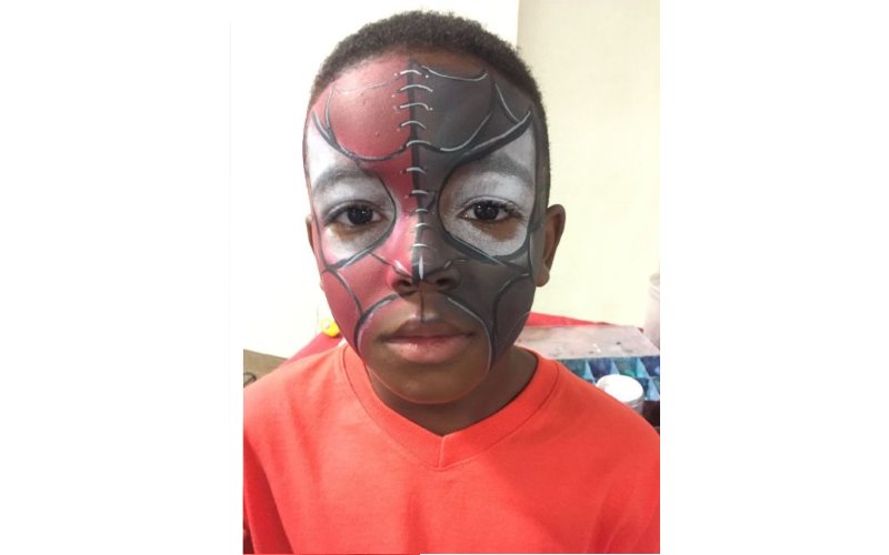 Image of a young boy with his face painted as spiderman