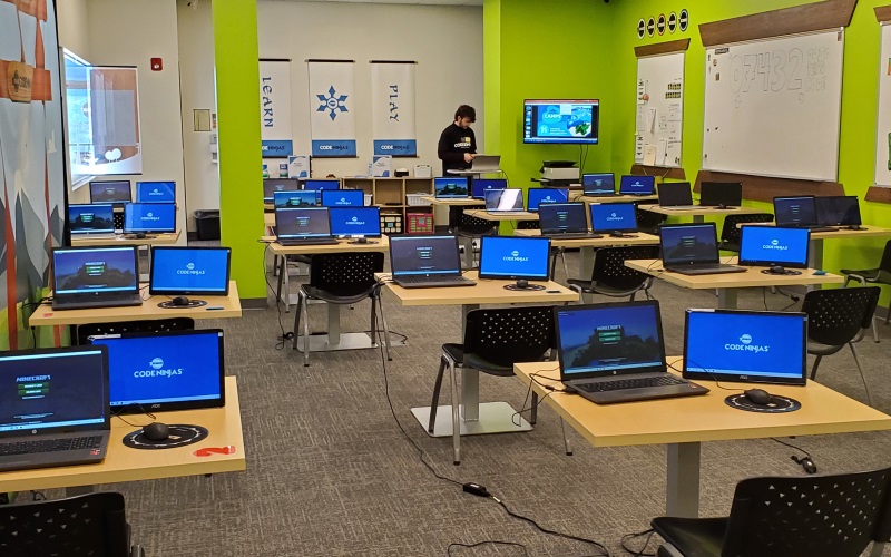 Image of Code Ninjas classroom with multiple computers on desks. 