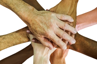 Image of multiple people putting their hands together to display corporate team building and bonding in NJ