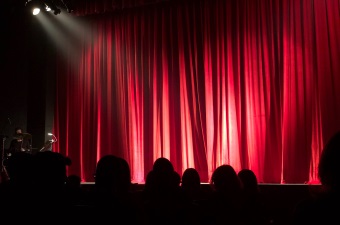 Image of a stage and silhouettes of people waiting for the show