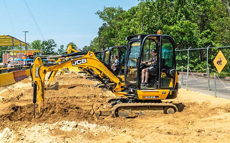 Girl uses a JCB mini excavator to dig at Diggerland USA theme & water park in West Berlin, NJ