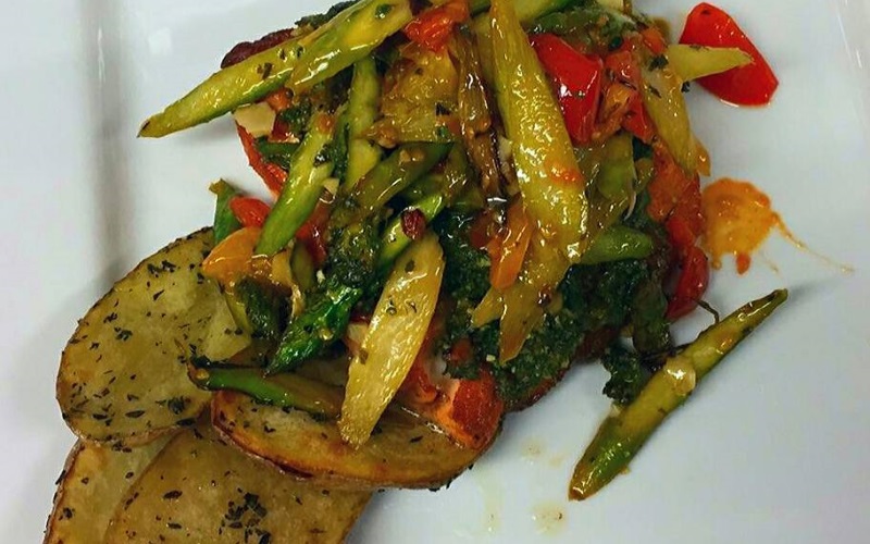 Image of a potato dish with various colorful veggies like yellow peppers and oregano on top