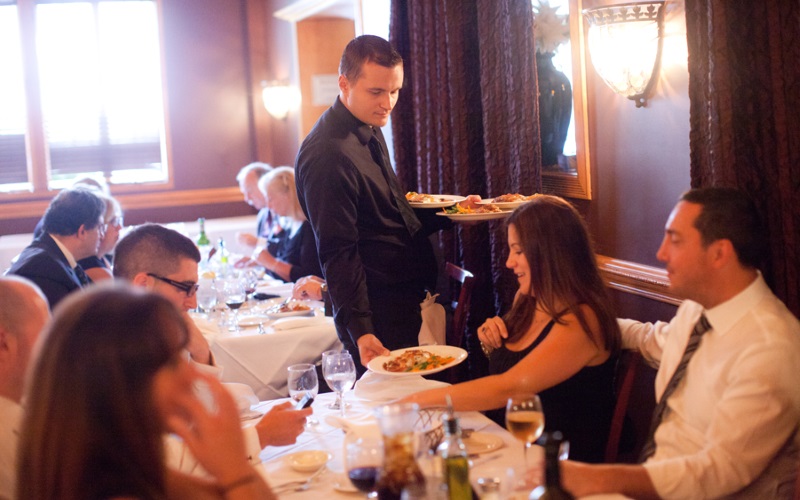 Image of a waiter serving a table food in Paisano's 