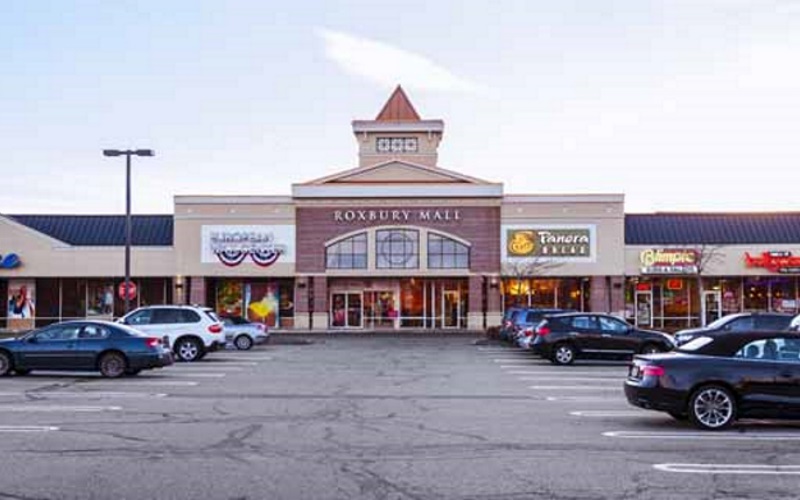 Image of the Roxbury Mall store front and parking lot with cars in the parking spots